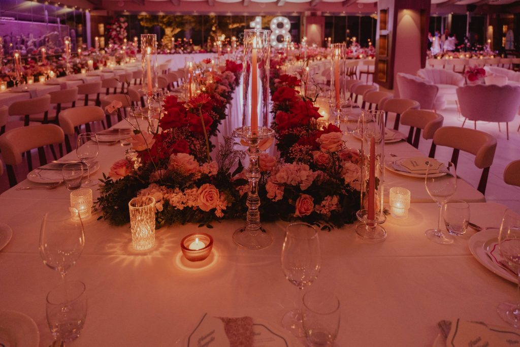 Un centrotavola di rose rosse e candele, con il 18 luminoso sullo sfondo