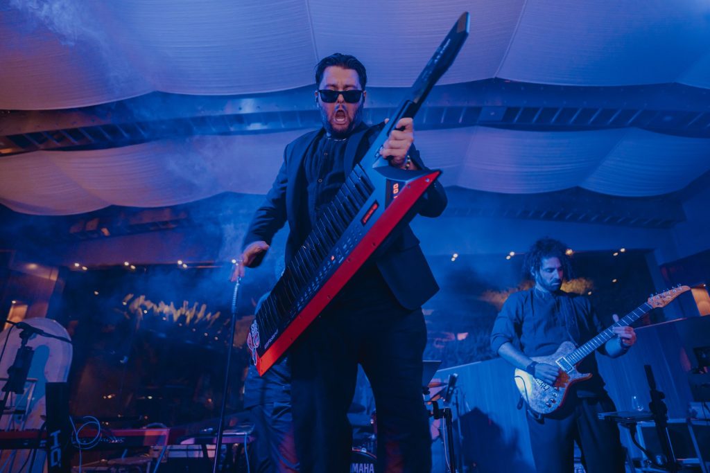 La band dal vivo sul palco, in luce blu