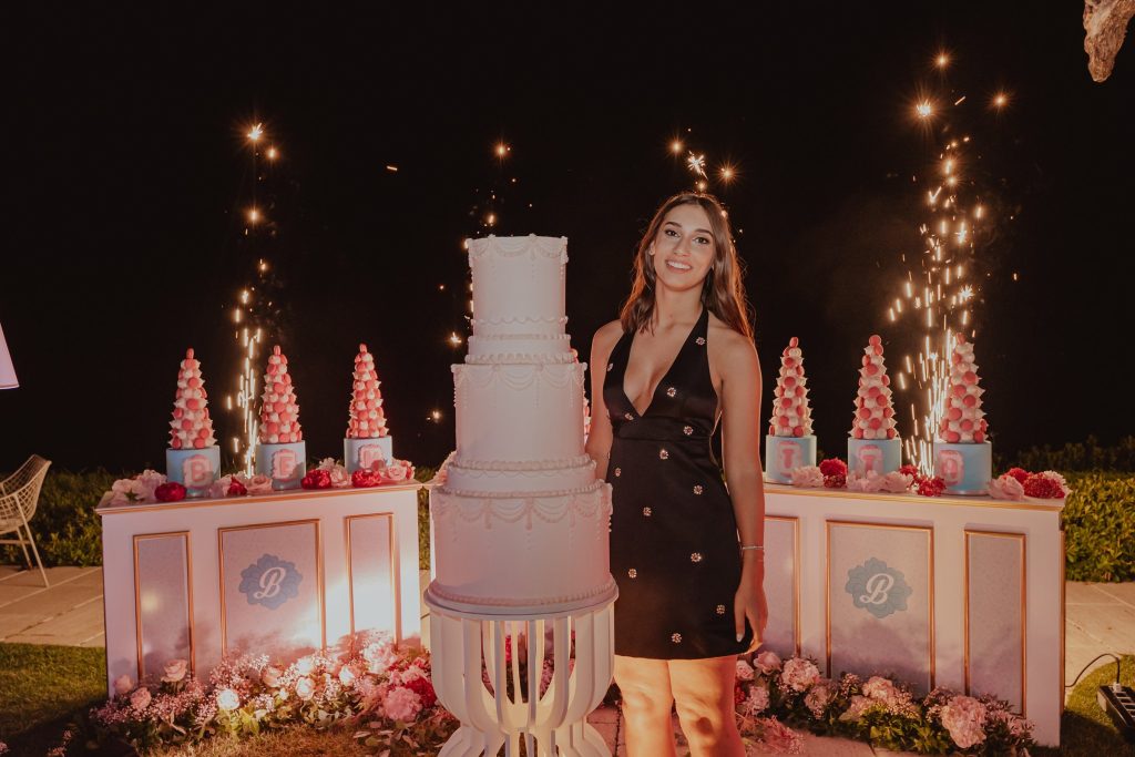Benedetta accanto alla torta, tra le fontane luminose