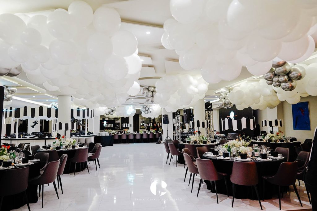 La sala allestita con un soffitto di palloncini bianchi e i tavoli rotondi