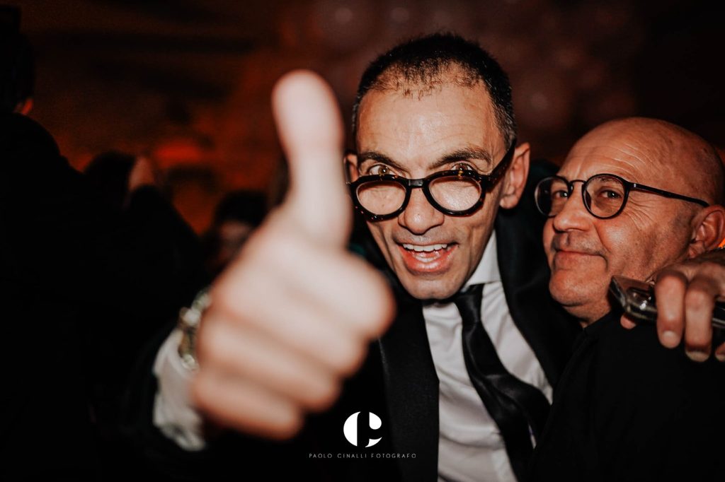 Angelo con il pollice alzato, abbracciato a un amico