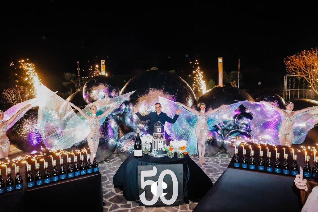 Il giardino di notte: sfere specchiate, performer con le ali di luce e il grande 50