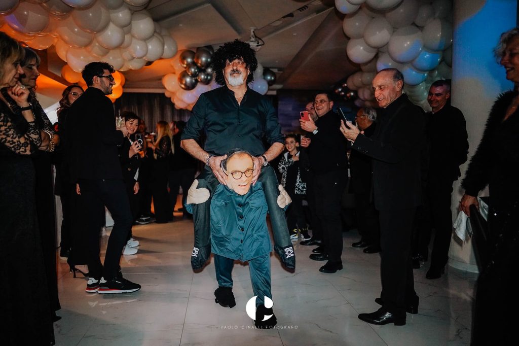 Un amico entra in sala con il costume del piccolo Angelo