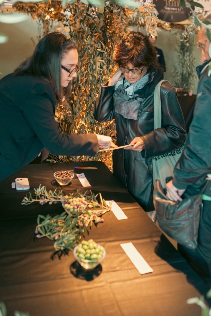 Un'ospite riceve la scheda del percorso al tavolo delle olive