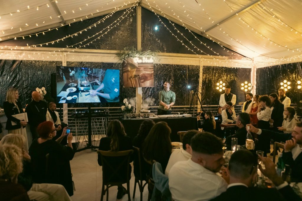 Gli ospiti a cena seguono lo show cooking sul maxischermo