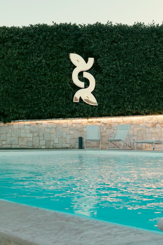 La piscina del frantoio con il logo Colle Raro sulla siepe